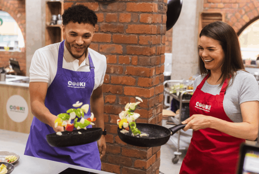 Two people cooking together in a teambuilding cookery session.